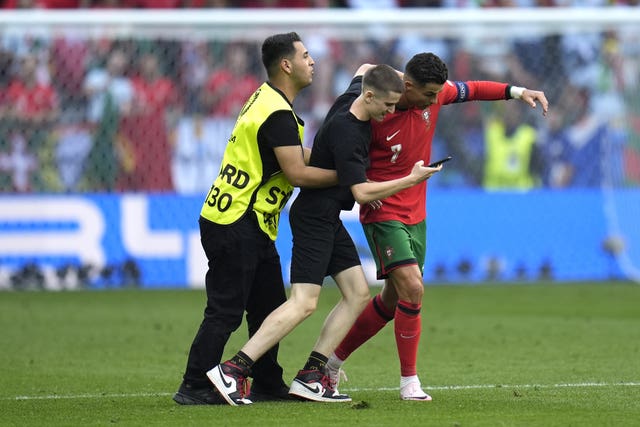 A pitch invader attempts to take a selfie with Ronaldo (Nick Potts/PA)