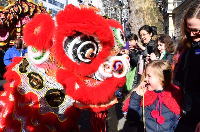 A Chinese Dragon gets up close to a young spectator along the parade route. (John Stillwell/PA)