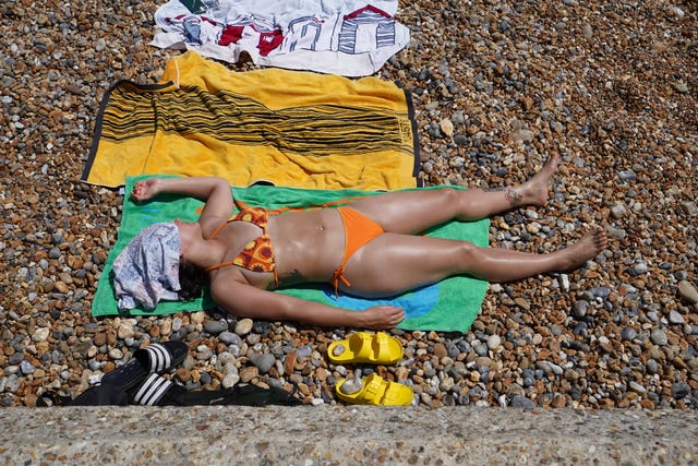 A woman sunbathes on the crowded beach at Brighton