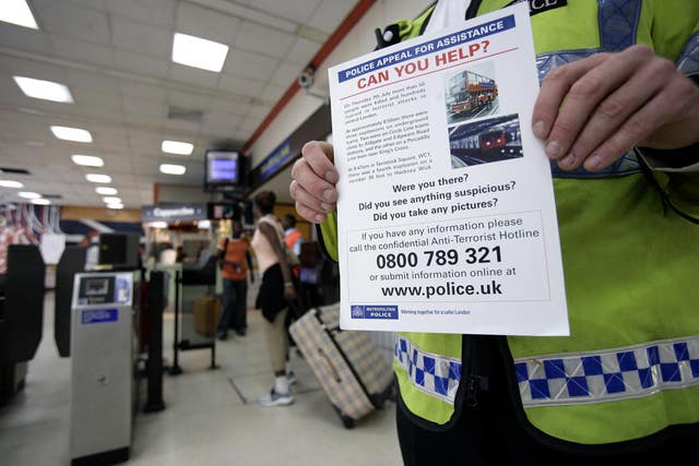 A police officer with a leaflet at Kings Cross station, London appealing for information into the bombings