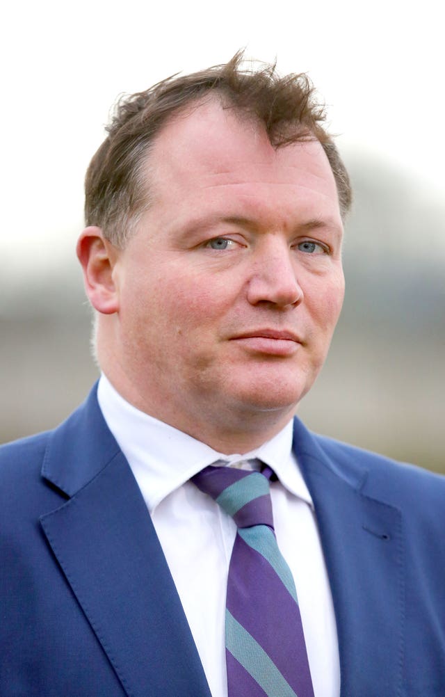 Headshot of Damian Collins in a blue blazer, white shirt and striped tie.