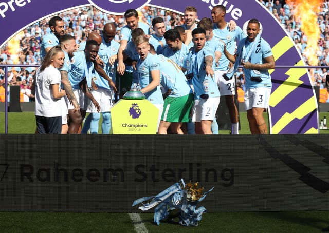 Manchester City players knock the Premier League trophy off the plinth 