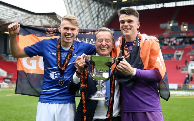 Hartlepool United’s Lewis Cass (left) and Brad James (right) with club president Jeff Stelling (centre) celebrate with the trophy