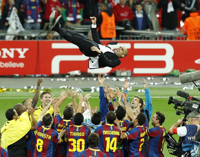 Barcelona’s players celebrate by throwing their manager Pep Guardiola up in the air. (PA)