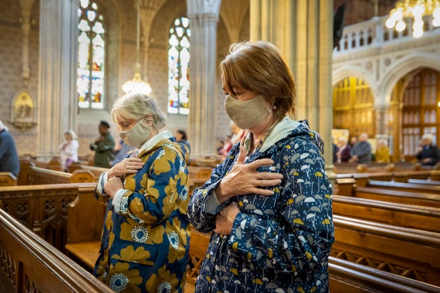 Parishioners wearing face masks bless themselves at the end of mass at St Patrick’s Catholic Cathedral in Armagh  (Liam McBurney/PA)