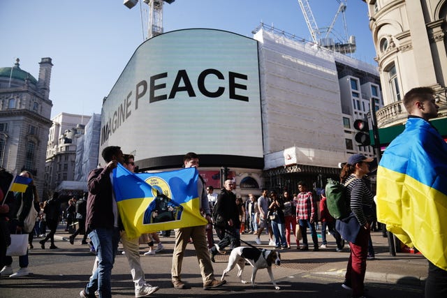 People pass the Yoko Ono Imagine Peace sign at Piccadilly, during a solidarity march in London for Ukraine (Aaron Chown/PA)