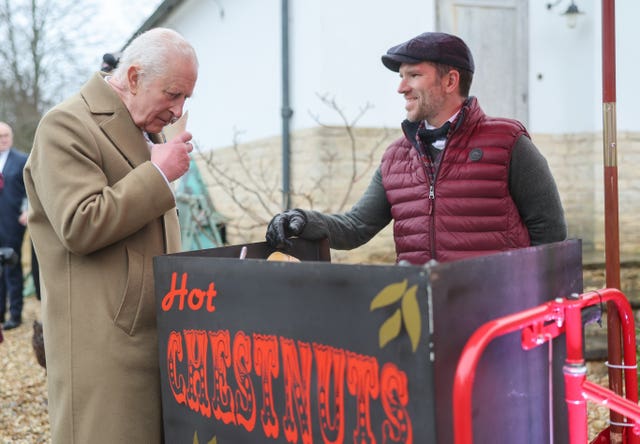 The King smells the roasted chestnuts handed to him by vendor Paul Venn