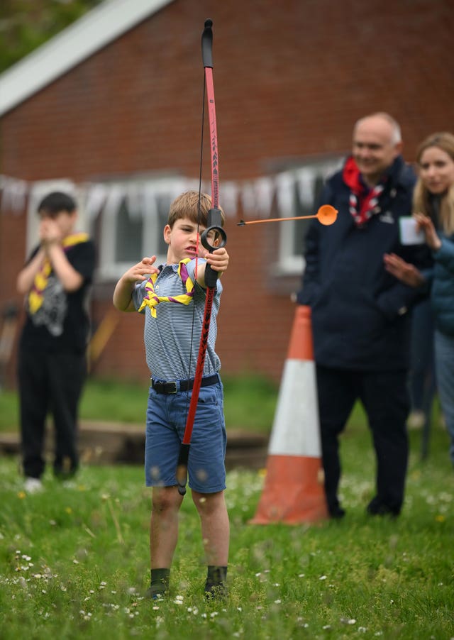 Prince Louis tries archery while joining volunteers to help renovate and improve the 3rd Upton Scouts Hut in Slough 