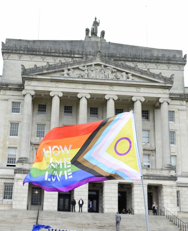 A trans flag being held up outside Stormont