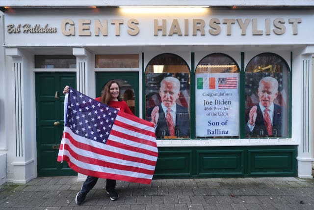 Doctor Catherine Hallahan prepares to hang an American flag inside her family’s hairdressers in Ballina, Co Mayo, to mark Mr Biden’s inauguration as the 46th President of the United States