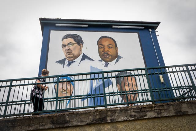 A woman walks past the Bogside mural in Derry City of John Hume, Martin Luther King Jr, Mother Teresa, and Nelson Mandela (Liam McBurney/PA)