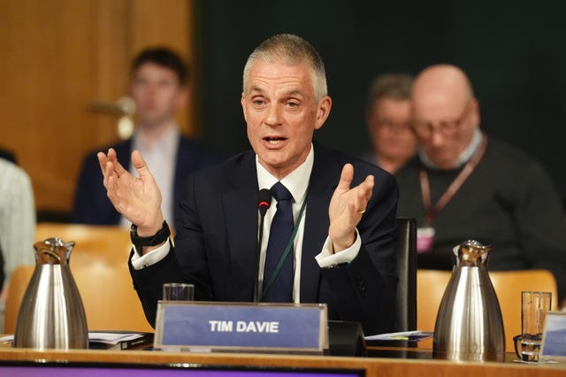 Tim Davie gesturing with his hands while speaking, seated in the Scottish Parliament