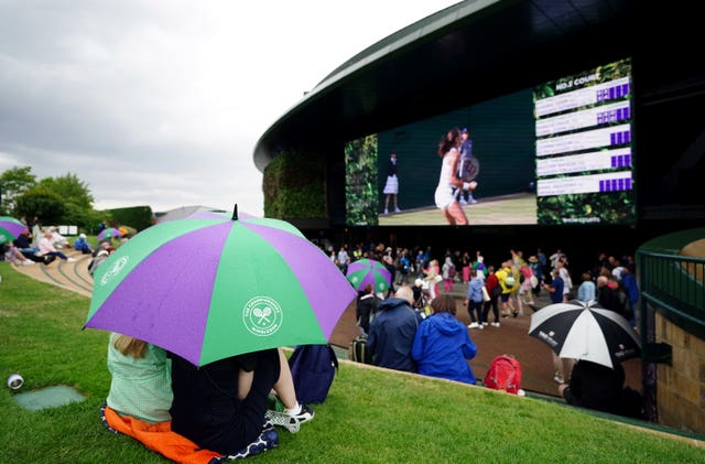 Spectators shelter from rain at Wimbledon