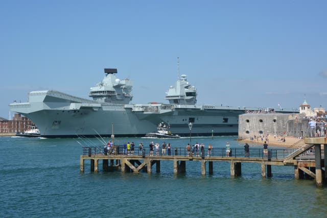 HMS Prince of Wales leaving harbour as people watch