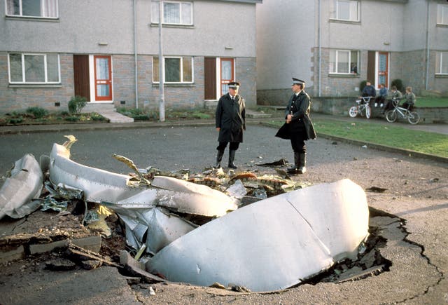 File photo of two police officers standing next to plane debris on a road