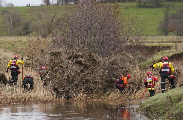 Members of a search and rescue team search through the debris in a river