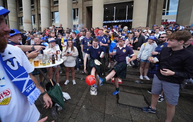 Scotland fans playing with a football while others drink in the centre of Stuttgart