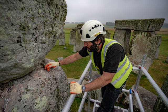Conservator James Preston uses a pointing spoon atop scaffold erected inside the stone circle at Stonehenge (Ben Birchall/PA)