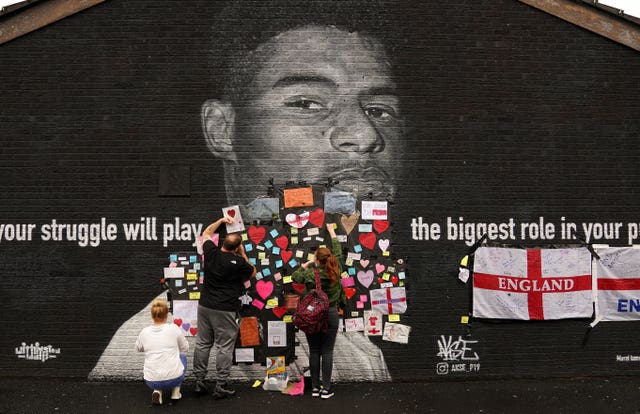 People place messages of support on top of bin liners that were taped over offensive wording on the mural of England forward Marcus Rashford 