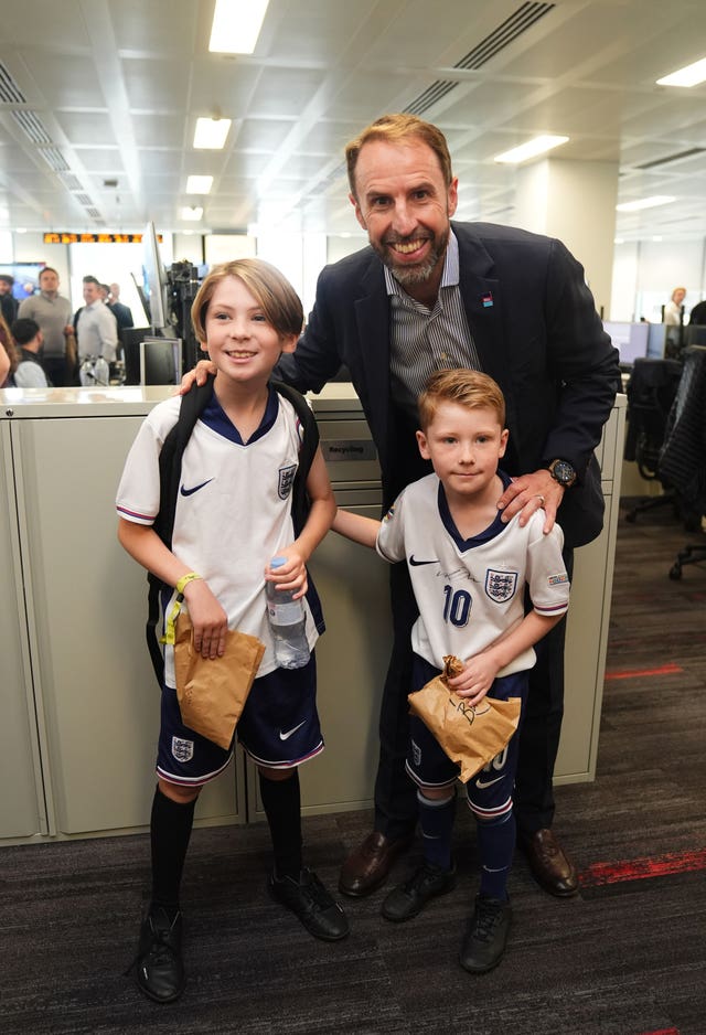 Gareth Southgate smiling as he poses with two young boys in England kits