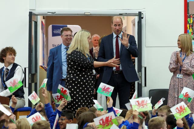 The Prince of Wales is welcomed to a school by cheering pupils 