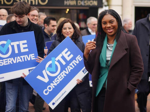 Kemi Badenoch standing in front of Conservative Party supporters holding placards